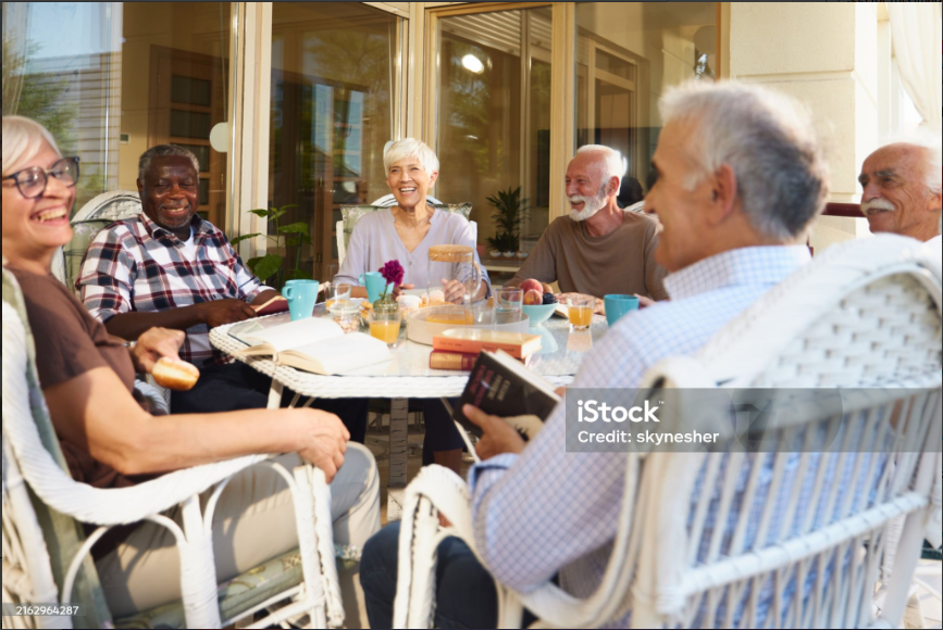 Group of independent seniors laughing and enjoying a meal together outdoors